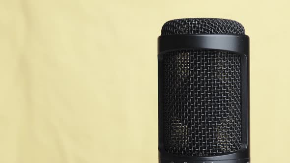 Studio Condenser Microphone Rotates on Yellow Background with Place for Text