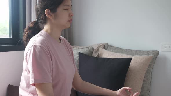 side view portrait of Asian woman sitting on couch practicing yoga