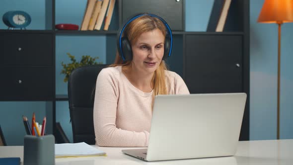 Mature Woman Sitting at Home Office Using App on Laptop for Video Call