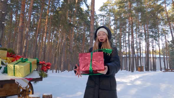 Excited Teenager Girl Catch Red Gift Box with Green Ribbon in Winter Snowy Forest
