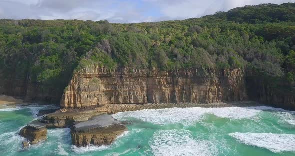 Beautiful aerial flight along high cliffs with trees and wild ocean, Australia