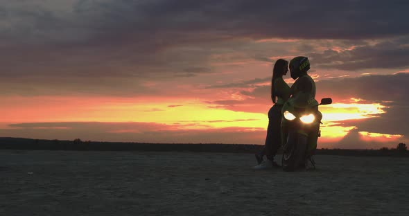 Couple Embracing Near Motorbike on Beach at Sunset