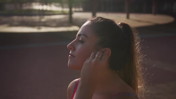 Caucasian woman putting on headphones in a park