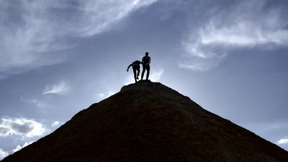 Silhouette of a Man Helps a Partner