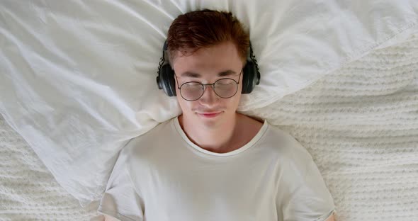 Calm young man enjoys listening chill music audio sound meditating feeling no stress at home. 