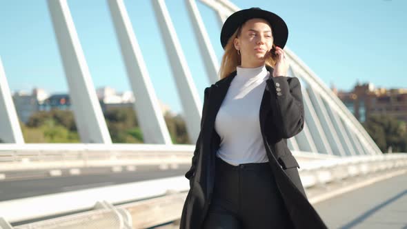 Young woman talking on mobile phone on bridge in sunlight