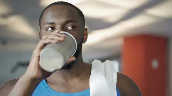 Handsome Man Drinking Protein Cocktail and Flirting in Gym, Smiling to Someone