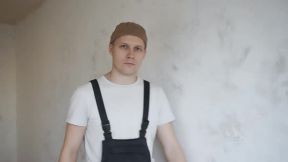 A Man in Construction Overalls Happily Shows a Paint Roller To the Camera