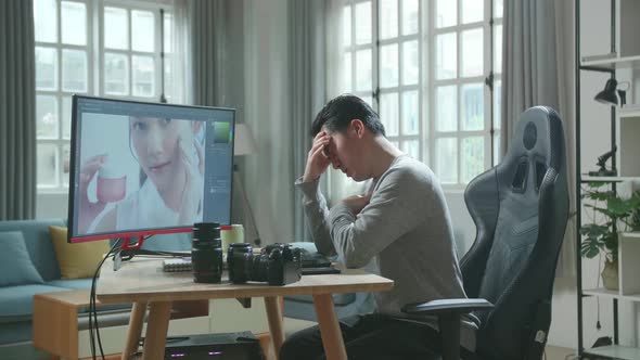 Asian Cameraman Being Tired While Using Desktop Computer For Editing Photo At Home