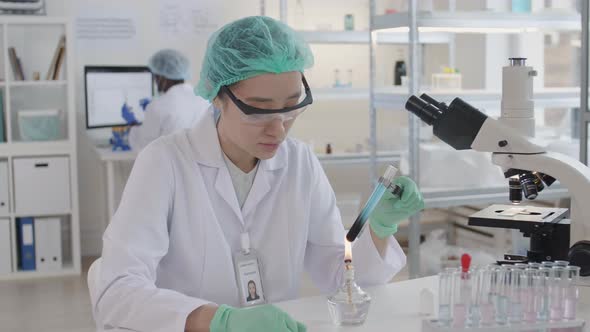 Female Virologist Heating Sample in Test-tube