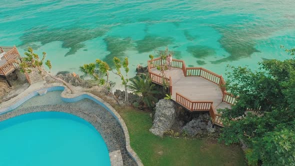 A Beautiful Light Green Coast with Reefs and a Loving Couple on the Balcony Above the Beach