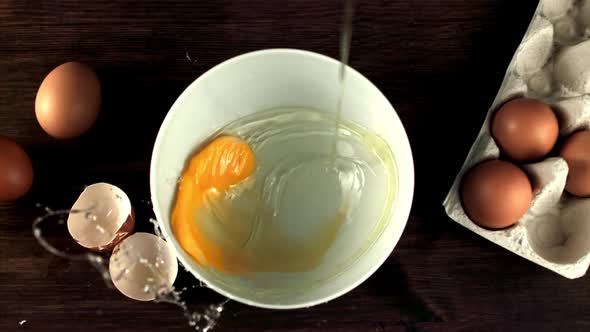 Super Slow Motion Raw Egg Falls Into a Transparent Bowl on the Table