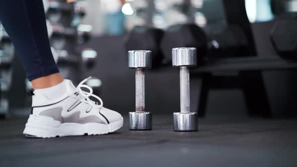 Female Feet Approaching Dumbbells in Gym