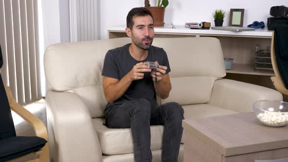 Adult Man Plays a Video Game on the Console in the Living Room