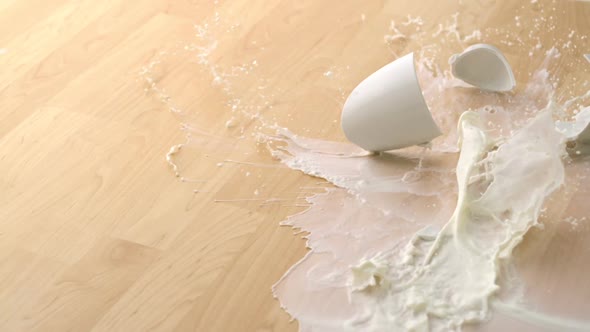 Dropping cup of milk and breaking on wooden floor, Slow Motion