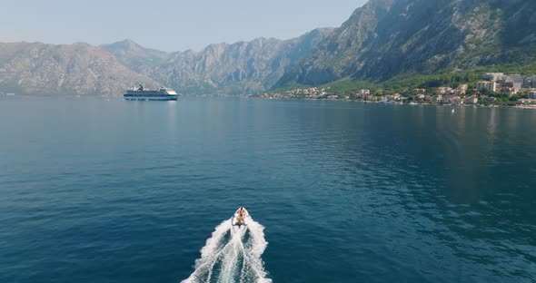 speeding boat towards a cruise liner with mountains on the background