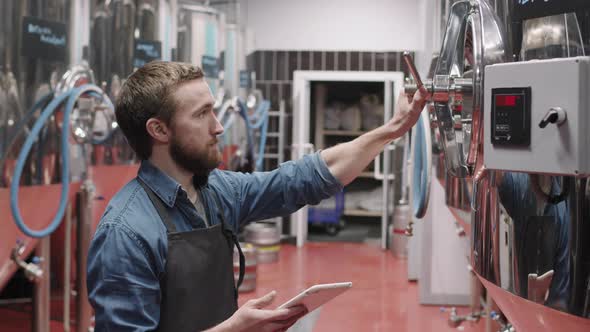 Male Brewery Worker Setting Parameters On Brew Equipment