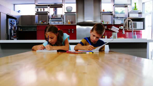 Siblings doing their homework in kitchen