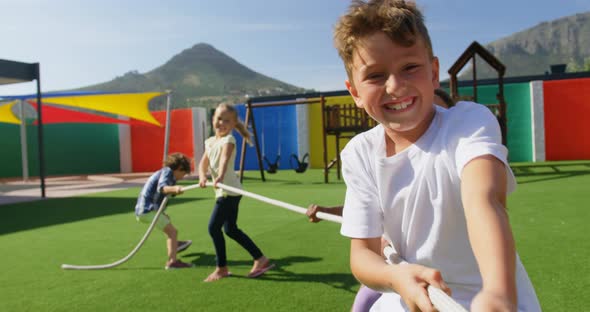 Front view of mixed-race schoolkids playing tug-of-war in the school playground 4k