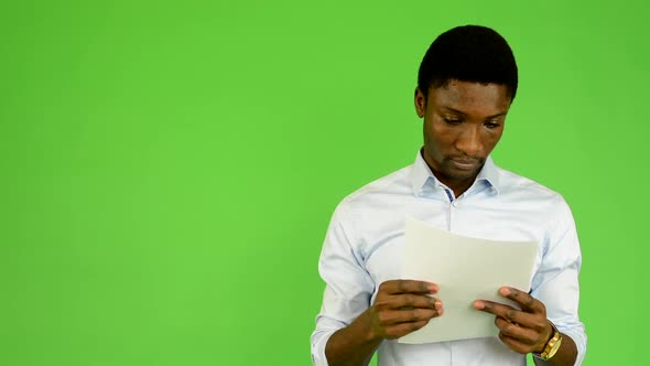 Young Handsome Black Man Reads Documents  - Green Screen - Studio
