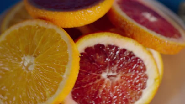 Juicy Ripe Slices of Red and Yellow Oranges in a White Plate Slowly Rotate