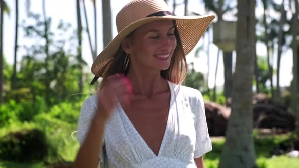 Portrait of Smiling Girl Vacationer in Straw Hat Among the Palms