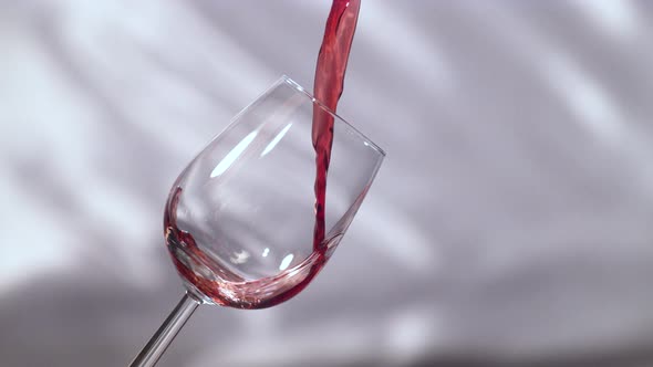 Pouring red wine on a grey background