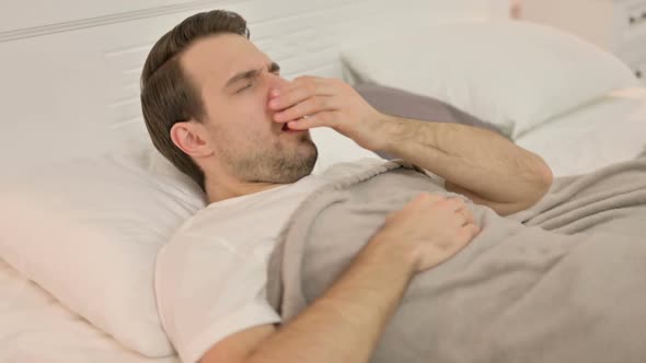 Sick Young Man with Cough Laying in Bed