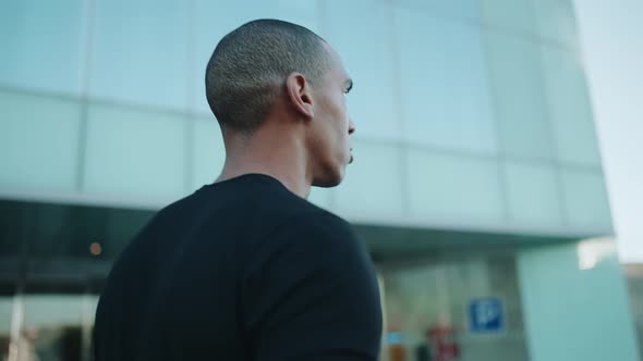 Strong bald sportsman wearing black t-shirt walking outdoors