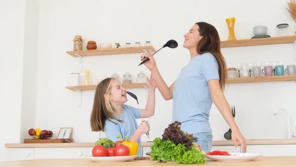 Mother Dances and Sings with Her Daughter in a Modern Kitchen