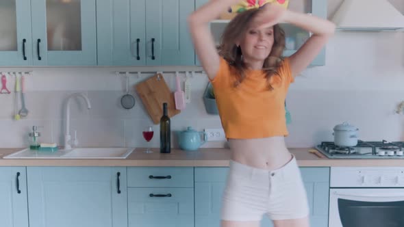 A Beautiful Woman in White Shorts is Relaxing at Home Dancing in the Kitchen