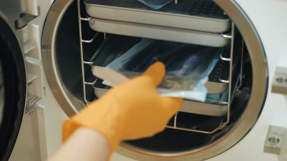 Laboratory Worker Putting Medical Instruments Into Steam Autoclave Sterilization Machine