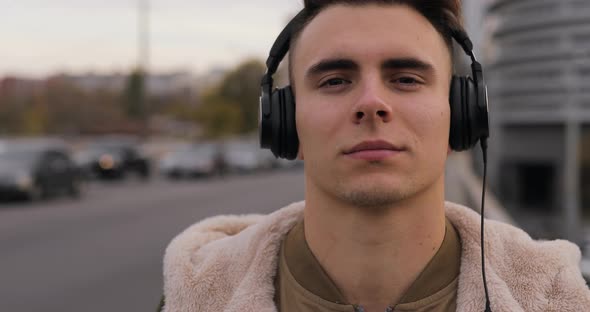 Man Puts on Headphones in City Listening Music