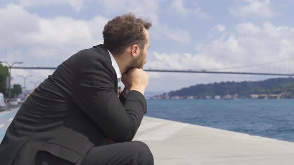 Thoughtful businessman in suit by the sea in the city.