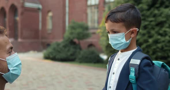 Crop View of Young Father and His Son Wearing Medical Protective Masks Embracing at Yard