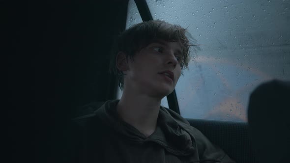 Hipsterlooking Young Man Sits in a Car in the Rain and Gives an Interview Into the Lavalier