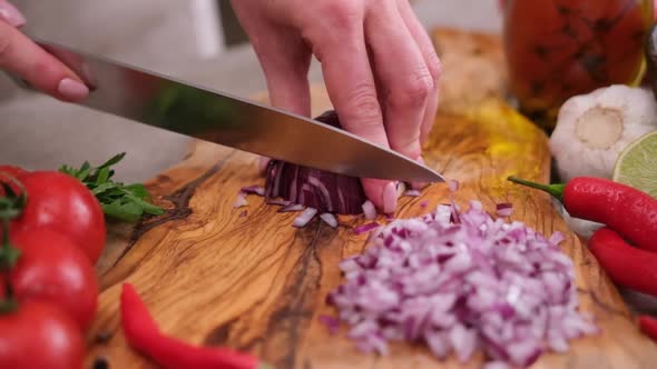 Woman Chopping Red Onion on Wooden Board at Domestic Kitchen