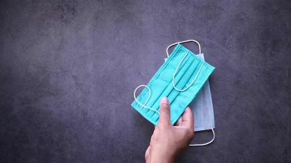 Top View of Man Hand Putting Surgical Mask on Black Background 