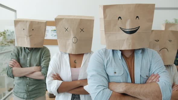 Portrait of Businesspeople Wearing Paper Bags with Emoji on Heads Standing with Arms Crossed in
