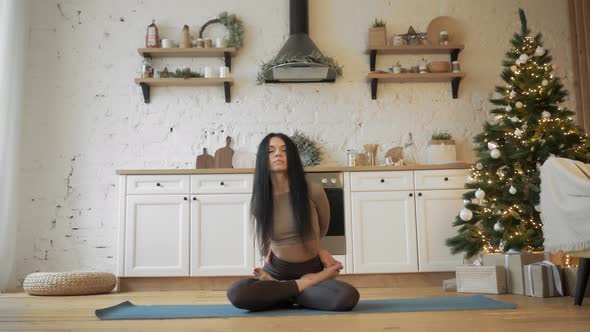 A Relaxed Young Woman in Sportswear Meditates in the Lotus Position Before the New Year