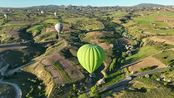 Hot air balloons fly over the mountainous landscape of Cappadocia, Turkey.