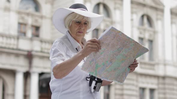 Senior Female Tourist Exploring Town with a Map in Hands. Looking for the Route