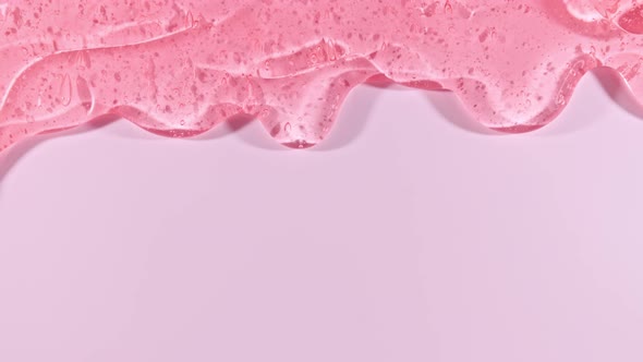 Pink Transparent Cosmetic Gel Fluid With Molecule Bubbles Flowing On The Plain Surface