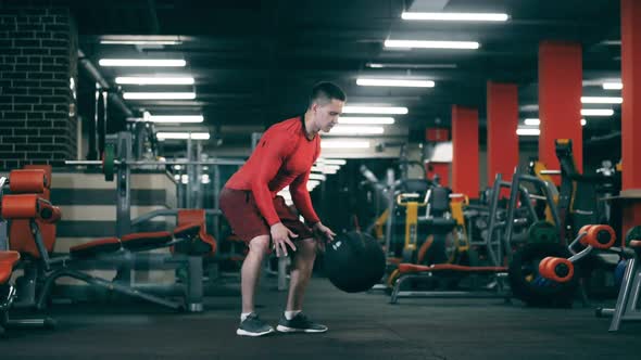 Young Man Trains with a Ball in Gym