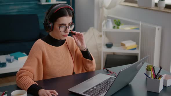 Young Woman Attending Video Call Meeting on Laptop with Headphones