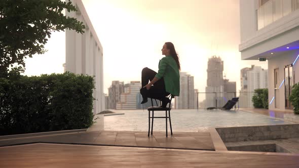 Dancer Crouching On Chair Then Raising Leg At Poolside