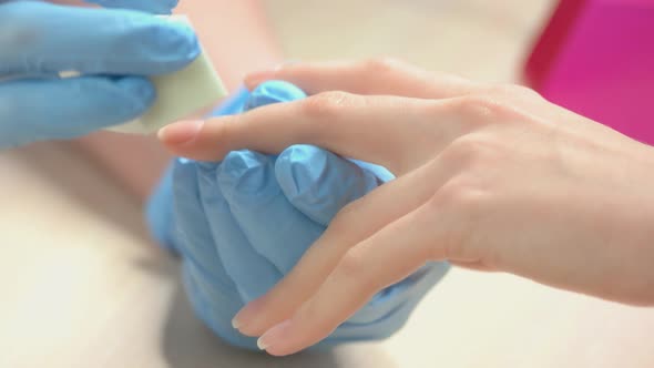 Beautician in Gloves Polishing Nails To Client