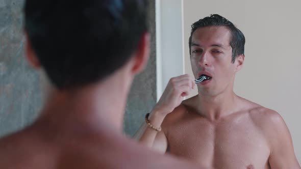 Young Man Brushing His Teeth in Bathroom in the Morning and Stop Because of a Tooth Pain Standing in