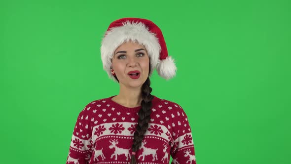 Portrait of Sweety Girl in Santa Claus Hat Is Saying Wow, Waves Her Head Approvingly and Showing