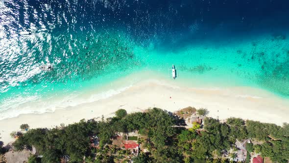 Beautiful tropical beach with white sand washed by blue turquoise water of calm lagoon reflecting su